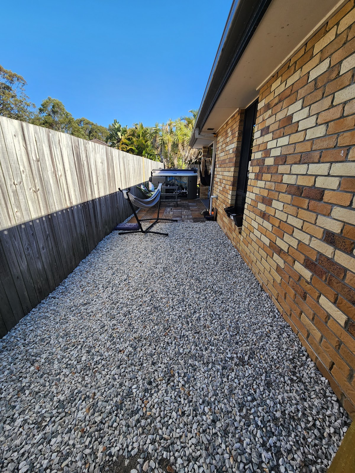 Gravel side path running along a brick house and timber fence