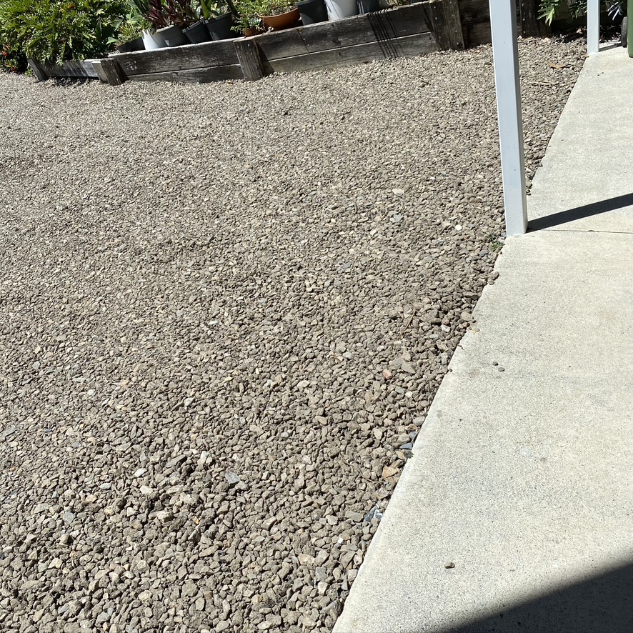 Fresh gravel laid beside a concrete path and timber sleeper planters